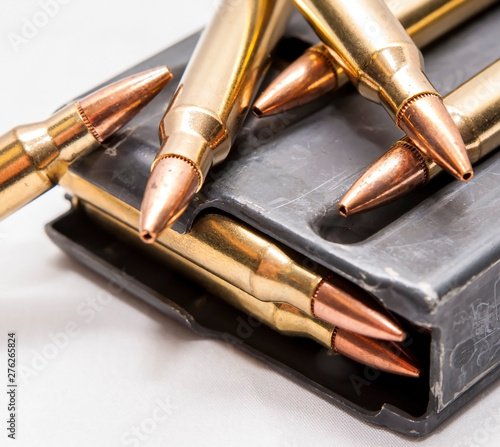 223 caliber bullets along with a loaded 223 caliber rifle magazine on a white background photo