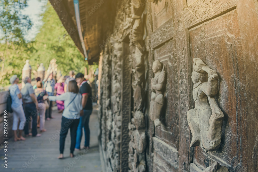 Group of tourists come to visit and take photographys at Shwe Nan Daw Kyaung (Golden Palace Monastery) in Mandalay, Myanmar. Selective focus on Wood Carving. Group of tourists come to visit and take photographys at Shwe Nan Daw Kyaung (Golden Palace Monastery) in Mandalay, Myanmar. Selective focus on Wood Carving.