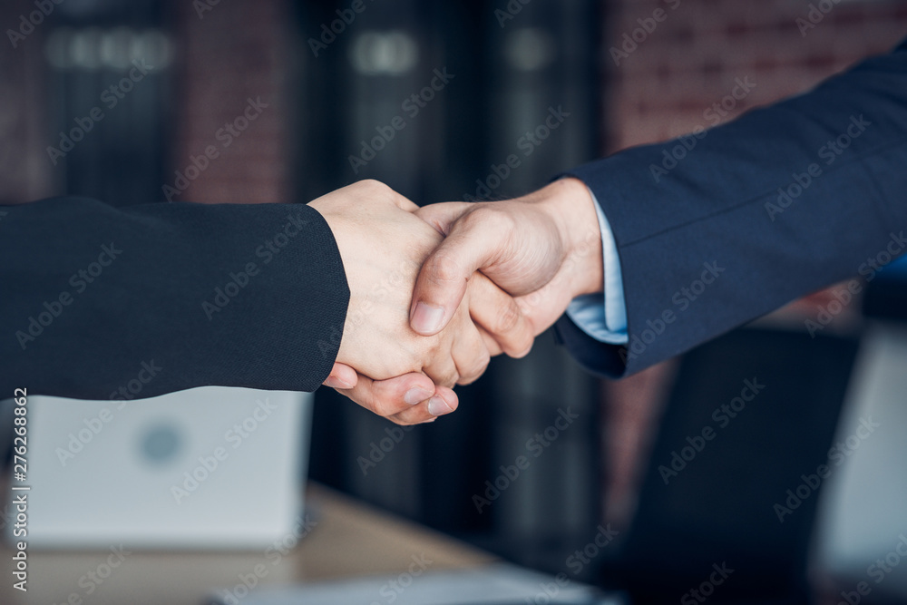 Close up handshake between businesswoman and businessman at meeting room in modern office.