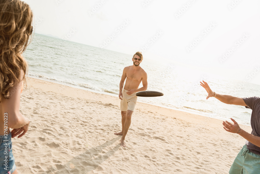 Fototapeta premium Group of friends playing gliding disc at the beach