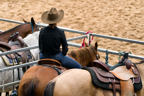 Fotografie Female cowboy sitting on horse with western saddle at rodeo arena – country life