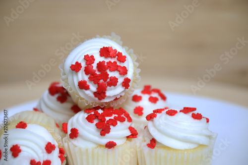 Canada Day cup cakes on a white plate with a wooden wall and table photo