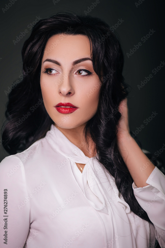 Stylish woman on a gray background with red lips. Business woman. In classic style, white shirt and black skirt. Stylish woman on a gray background with red lips. Business woman. In classic style, white shirt and black skirt.