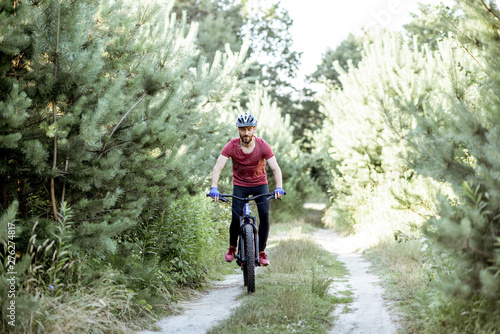 Cyclist riding mountain bicycle on the forest road during the summer time