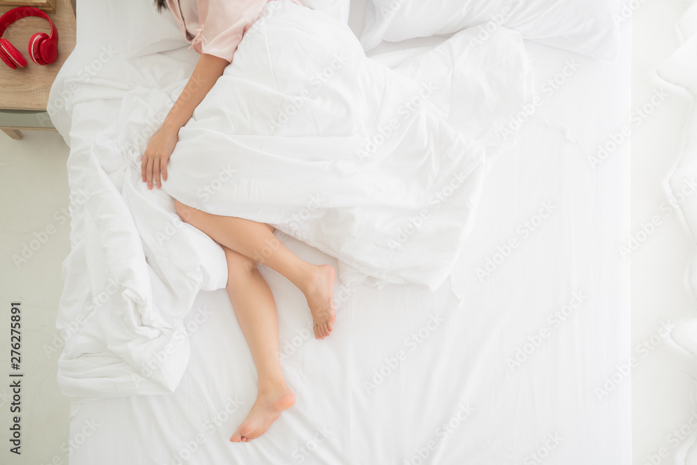 Beautiful crossed woman legs relaxing lying on bed with white duvet in bedroom, top view, copy space Beautiful crossed woman legs relaxing lying on bed with white duvet in bedroom, top view, copy space