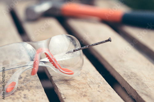 broken safety glasses, nail and hammer, concept of an accident at work.	