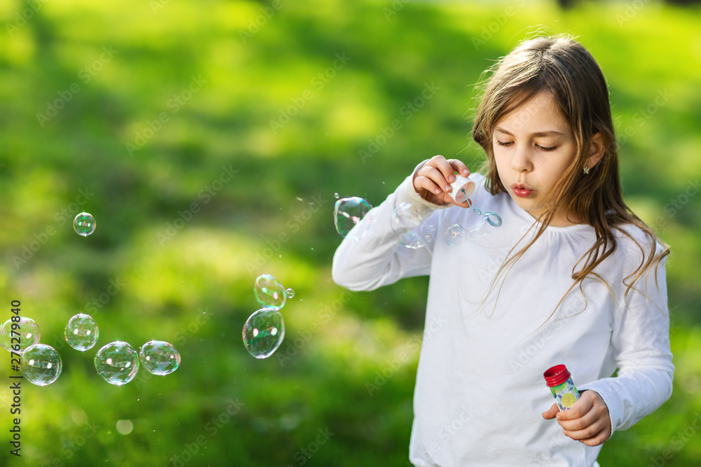 young girl blowing soap bubbles in park young girl blowing soap bubbles in park