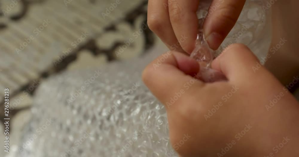 Child fingers bursting air pockets in a sheet of transparent bubble wrap Child fingers bursting air pockets in a sheet of transparent bubble wrap