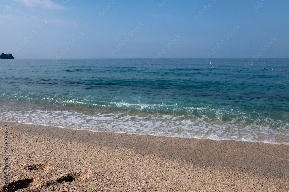 Sunny sandy beach with sea waves. Tropical landscape. Coast sea or ocean. Beautiful background.