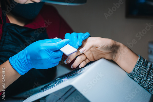 Manicurist. A girl with blue gloves makes a manicure. The process of manicure.