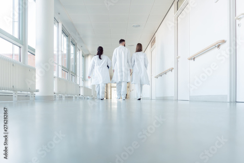 Three doctors walking down a corridor in hospital photo