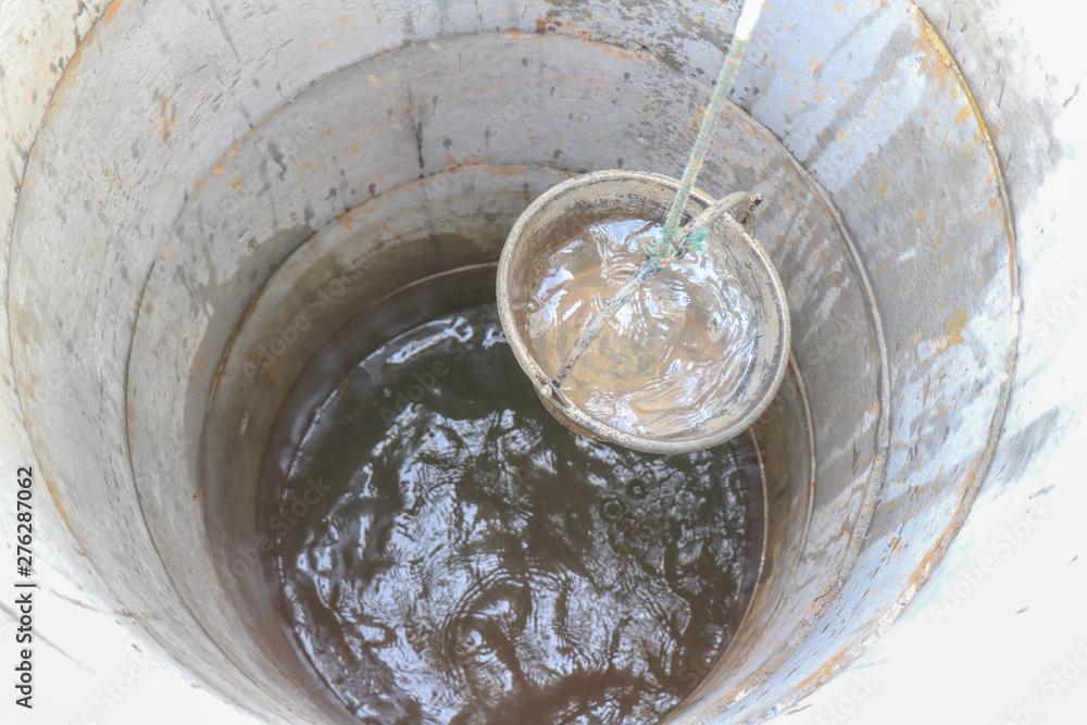 pulling out bucket full of drink water from the well, view of the water