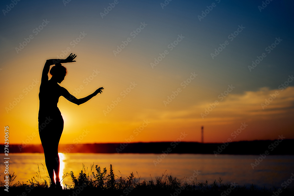 girl dancing on the beach in the setting sun. silhouette image.