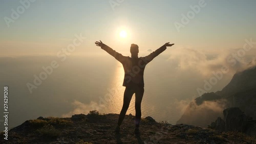 Wallpaper Mural Silhuette Young Woman arms outstretched observing a beautiful dramatic sunset above a sea from a high mountain in Crimea. Torontodigital.ca