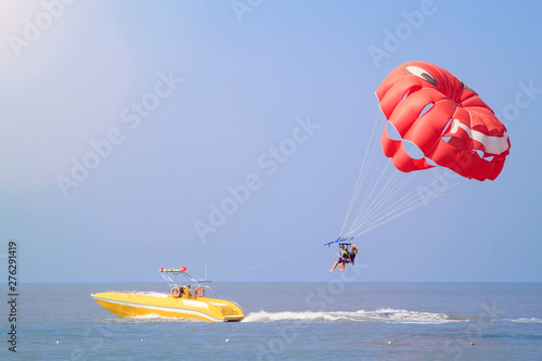 Fototapeta Naklejka Na Ścianę i Meble -  Parasailing - active form of recreation, in which person is fixed with long rope to moving boat and thanks to presence of special parachute hovers through air