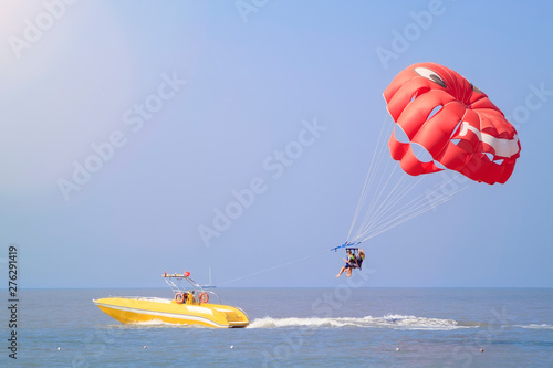 Parasailing - active form of recreation, in which person is fixed with long rope to moving boat and thanks to presence of special parachute hovers through air photo