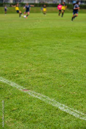 White outline for a football field for a Girl's Under 15 years school soccer tournament. Focusing on the football field with blurry football players in action as a background.