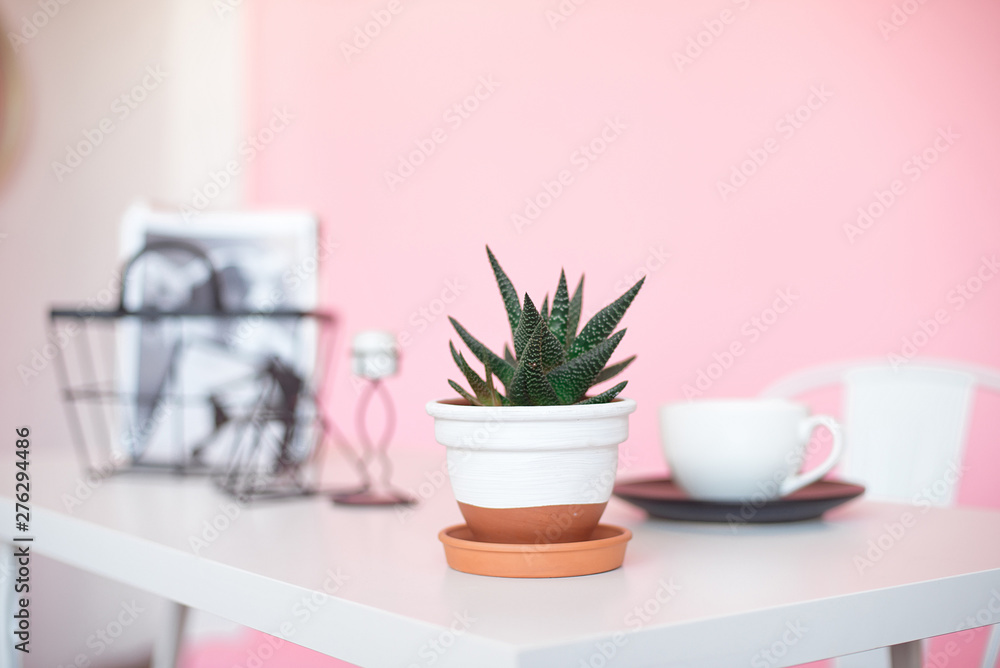 White table desk with copy space, supplies and a coffee mug pot with a flower on a pink background. Front view and copy space White table desk with copy space, supplies and a coffee mug pot with a flower on a pink background. Front view and copy space
