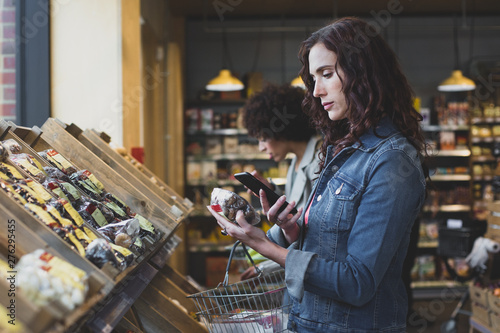 Young adult female using self scan in a grocery store photo