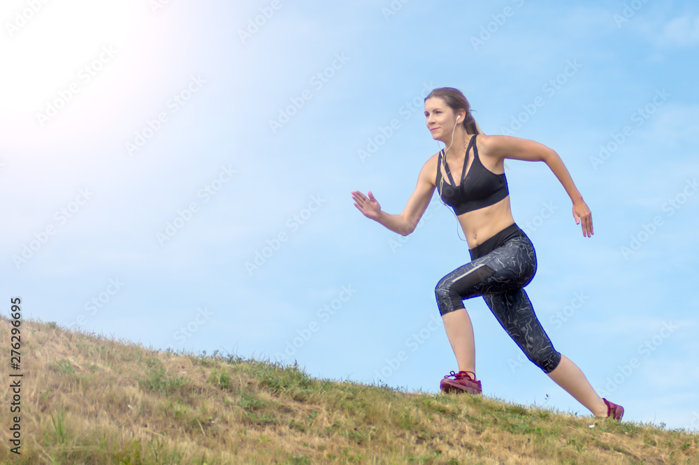Side view beautiful woman running on the edge of the hill. background blue sky Side view beautiful woman running on the edge of the hill. background blue sky