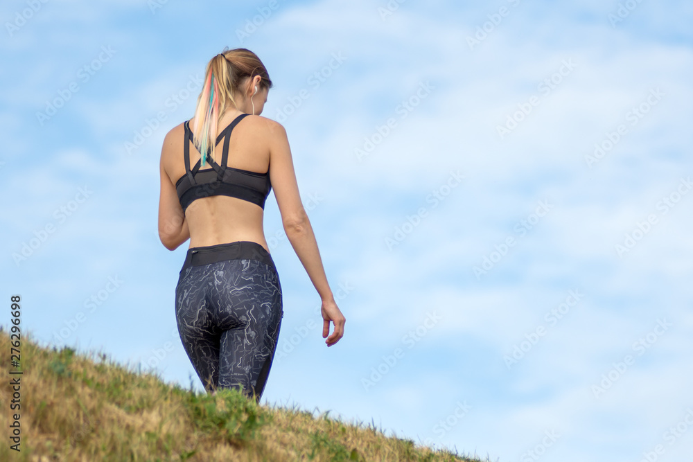 Back view woman walking after jogging in the park. Fitness and lifestyle concept. Back view woman walking after jogging in the park. Fitness and lifestyle concept.