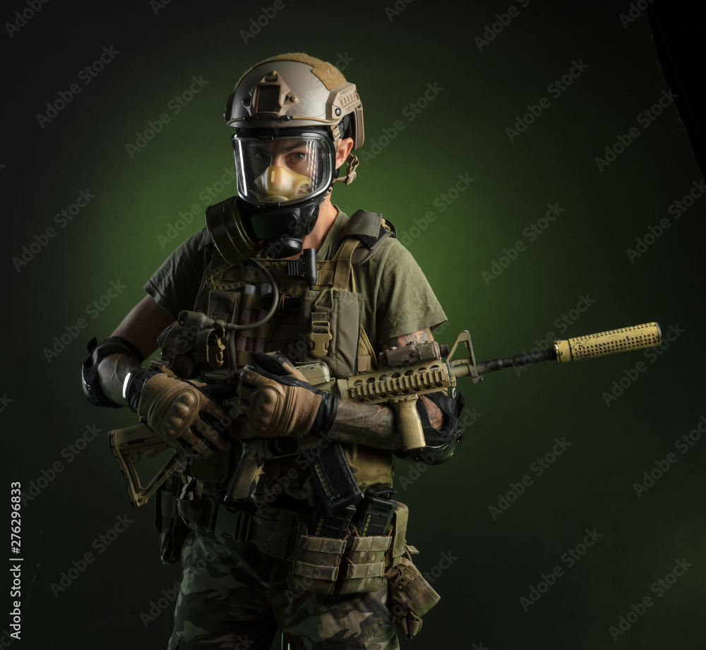 A guy in protective military clothing and a gas mask with a rifle