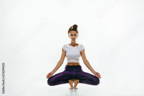 Sporty young woman doing yoga practice isolated on white studio background. Fit flexible female model practicing. Concept of healthy lifestyle and natural balance between body and mental development.