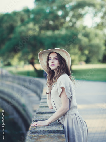 Portrait of charming girl in summer hat and dress looking away