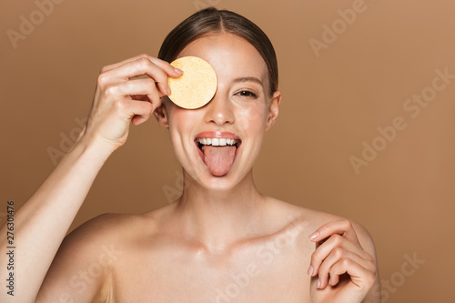 Papier peint Beautiful young amazing woman posing isolated over brown chocolate background wall holding makeup remover exfoliate pad