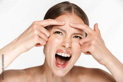 Displeased angry young woman posing isolated over white background wall squeeze out a pimple.