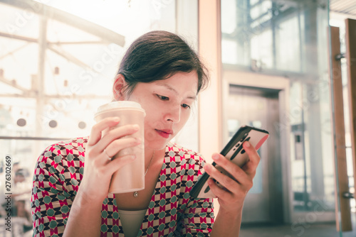 Woman at cafe drinking coffee and using mobile phone