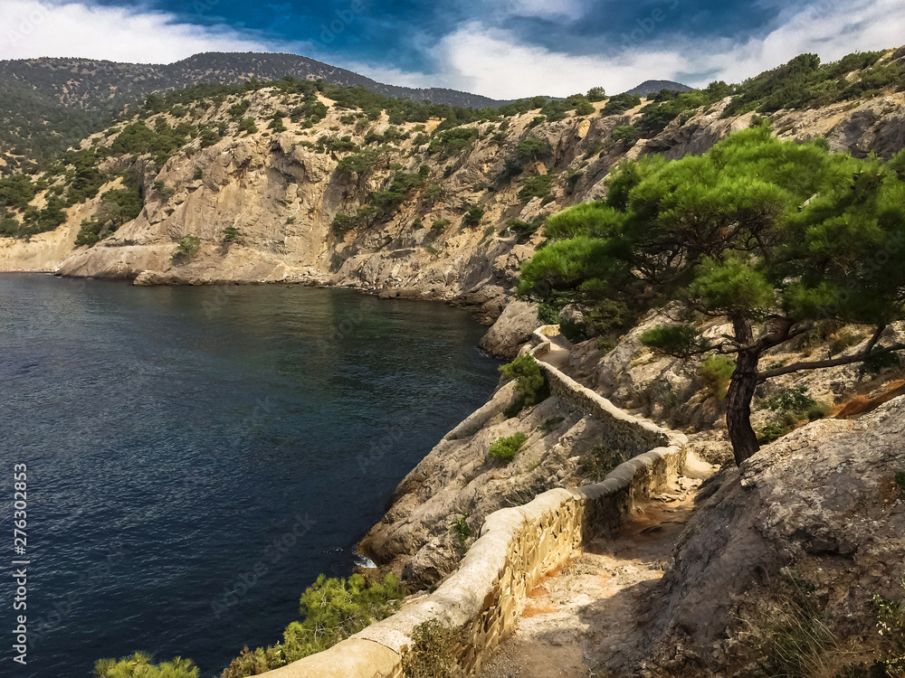 view of secluded sea bay in the summer from a mountain path surrounded by mountain cliffs with lush pine and ancient mountain path along the coast, idyllic seascape, Golitsina trail in the Crimea