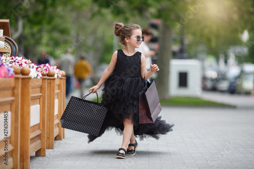 Cute little caucasian girl child having shopping fun.Fashion trend. Fashion shop. Little girl with bunch packages. Seasonal sale. Fashion girl customer. Happy child in shop with bags. Shopping day hap