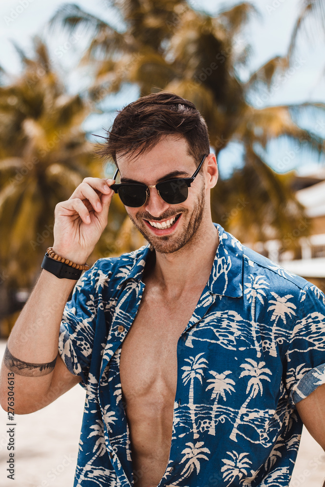 Handsome mature male model enjoying a sunny day on the beautiful island of Boracay. Walking with open blue shirt between palm trees on famous white beach. Handsome mature male model enjoying a sunny day on the beautiful island of Boracay. Walking with open blue shirt between palm trees on famous white beach.