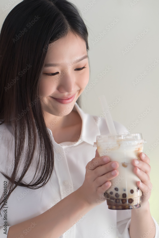 Happy smiling asian woman drinking iced bubble milk tea; aka boba tea