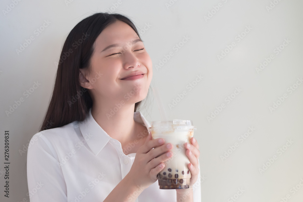 Happy smiling asian woman drinking iced bubble milk tea; aka boba tea