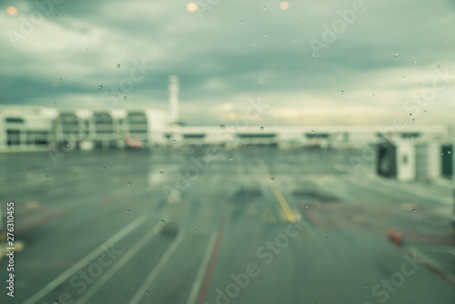 Rain drops on window of airport  monsoon season in South East Asia. Blurred aircraft and terminal. Transportation weather concept.