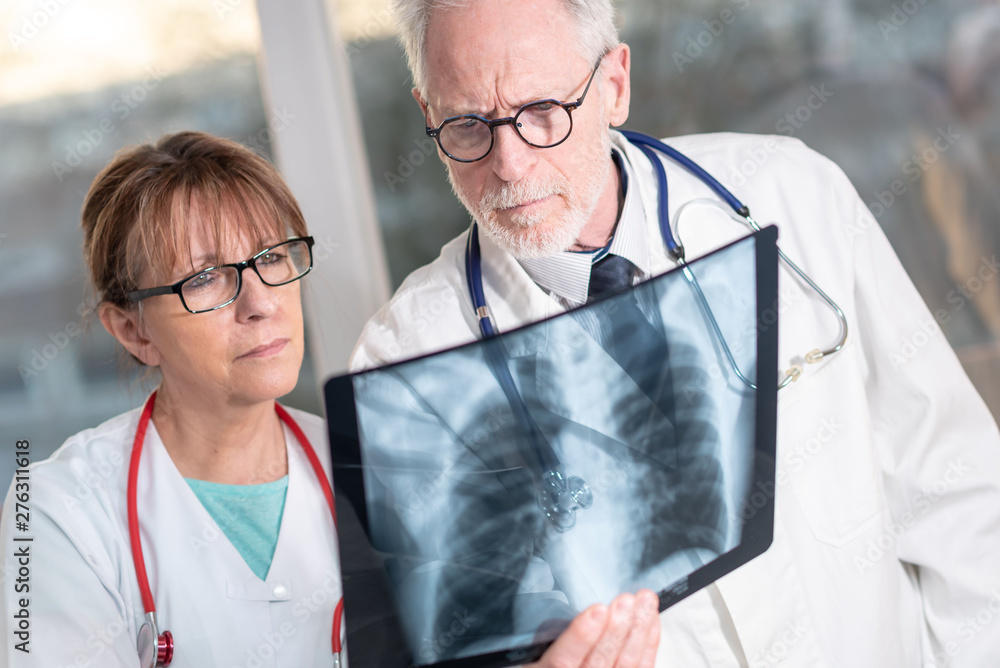 Two doctors examining x-ray report - obrazy, fototapety, plakaty 