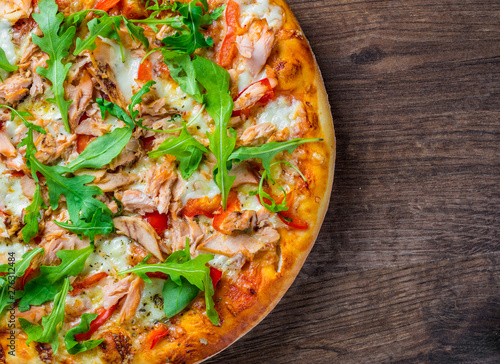 Pizza with Mozzarella cheese, salmon fish, tomato sauce, pepper. Italian pizza on wooden table background