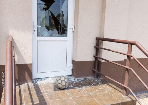  A football or soccer ball broke the window near football training area. Close-up, selective focus. 
