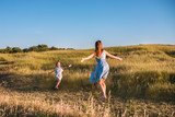 Young mother and daughter playing in a golden field of sunshine.