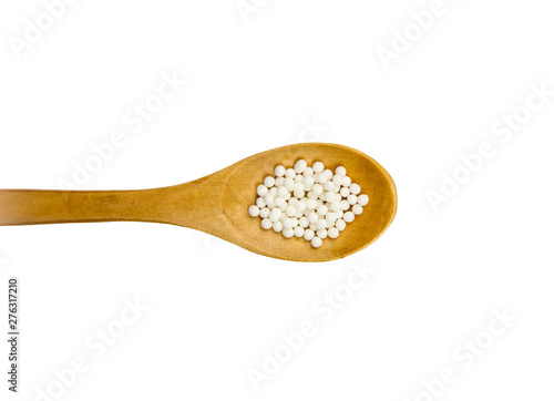 Wood spoon with small white round homeopathy pills isolated on white background, copy space.