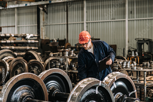 Man working at train factory, quality control check. photo