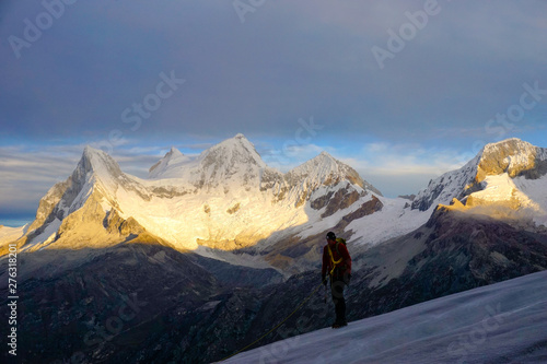 mountain climber on Nevado Pisco glacier at sunrise with the four peaks of Nevado Huandoy in the background