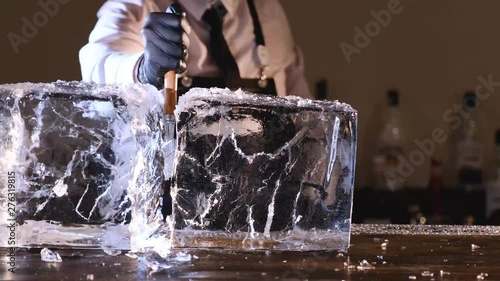 bartender splits a block of ice to cool cocktails, barmen splitting huge clear ice block to two parts by using an ice pick and hammer. slow motion 4k