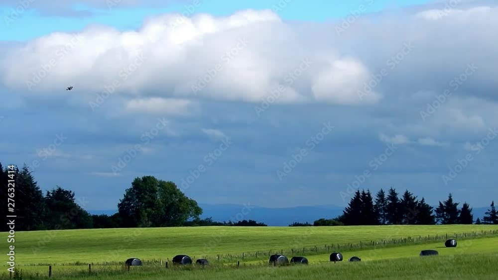 Small drone flight over farm field & plastic covered hay bales across landscape. Small drone flight over farm field & plastic covered hay bales across landscape.