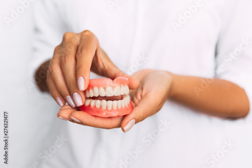 The dentist is holding dentures in his hands. Dental prosthesis in the hands of the doctor close-up. Front view of complete denture. Dentistry conceptual photo. Prosthetic dentistry. False teeth