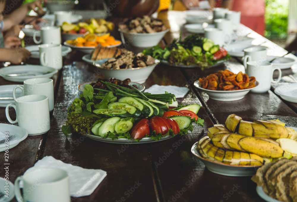 Vegetables and fruits are sliced on a wooden table. Picnic in the summer. Fresh vegetables. Party in nature.