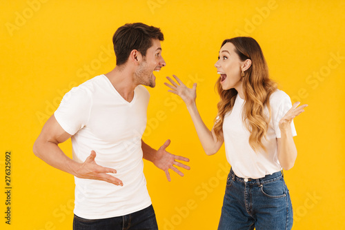 Portrait of happy couple man and woman in basic t-shirts rejoicing with gestures while looking at each other