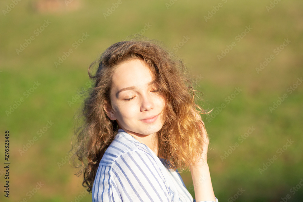 Portrait of beautiful young woman with closed eyes in summer park